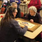 People around a table looking at a framed work.