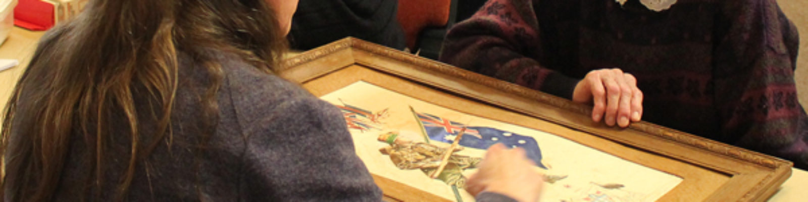 People around a table looking at a framed work.