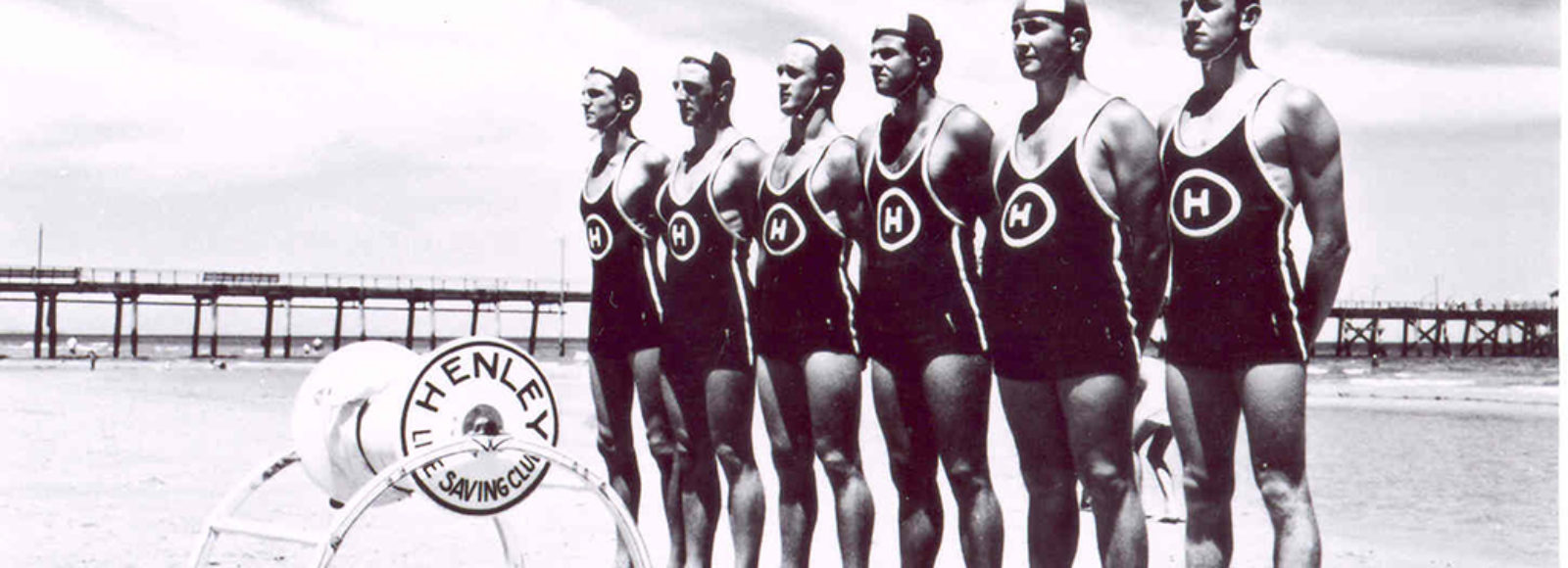Image: six life savers standing in a row on a beach