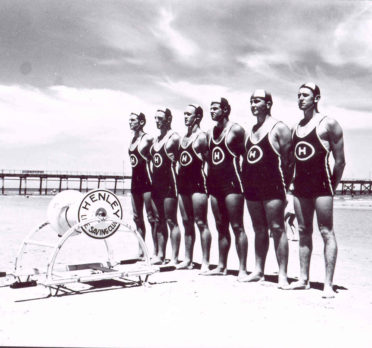 Image: six life savers standing in a row on a beach