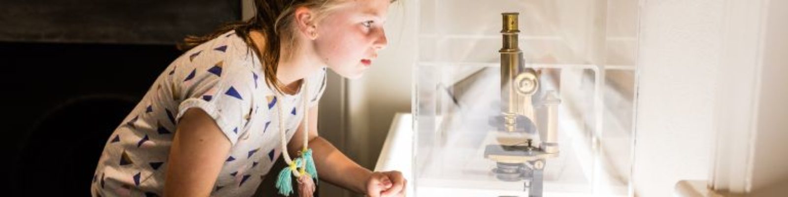 Young Child peering at a microscope