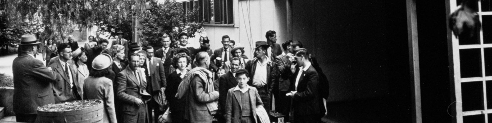 Group of people with suitcases in front of a building.