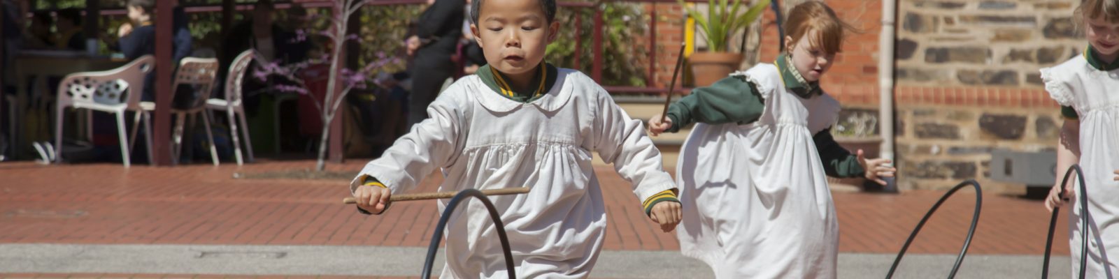 Young children running outside with hoops.