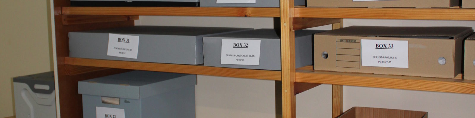 Shelves filled with grey archival boxes and brown cardboard boxes.