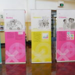 Row of five pull up banners in bright pink, aqua and yellow.