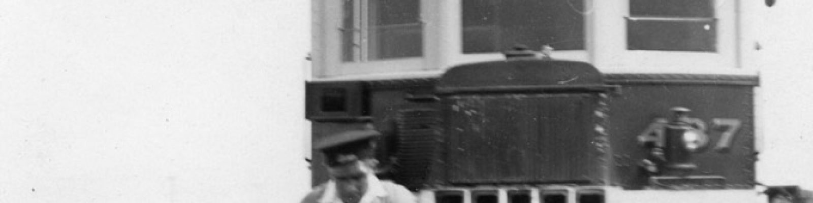 Man on a railway trike on tracks in front of a train.