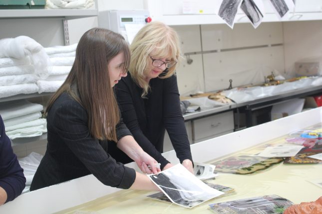 Two women holding large photograph in a table of water