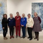 Group of smiling women in front of artworks in a gallery