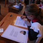 Child at old fashioned school desk writing with pen and ink