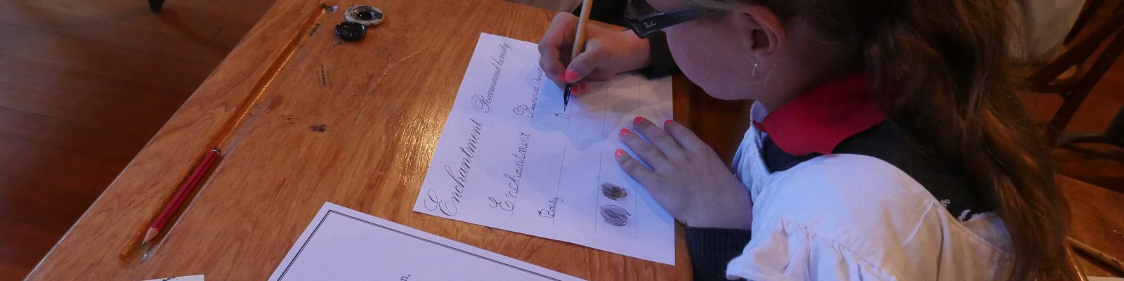 Child at old fashioned school desk writing with pen and ink