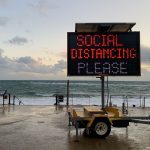 Digital sign reading 'Social Distancing Please'