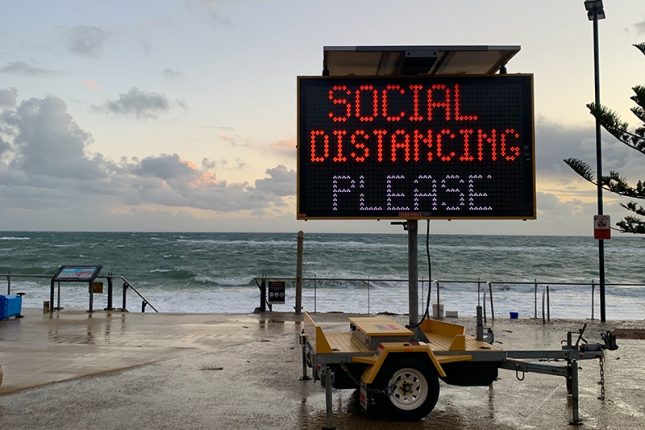 Digital sign reading 'Social Distancing Please'