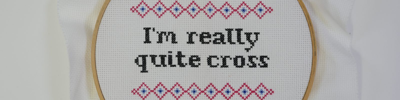 Embroidery hoop around cross stitch reading 'I'm really Quite Cross