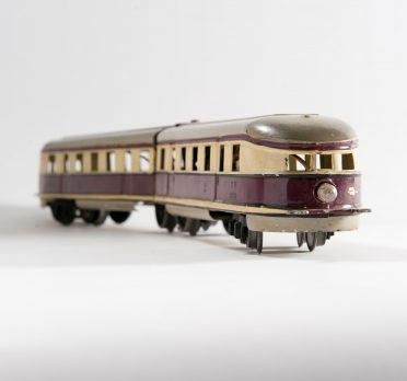 Toy tin train painted in a cream and brown stripe through the middle.