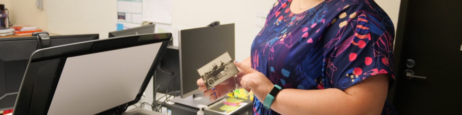 Woman holding a photograph in front of a flat bed scanner