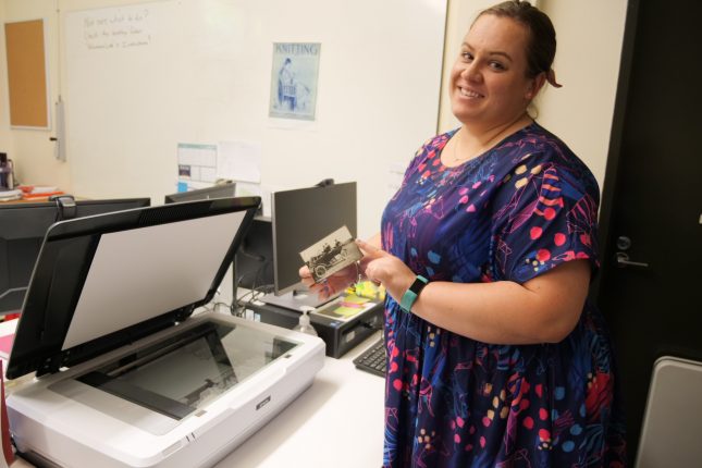 Woman holding a photograph in front of a flat bed scanner