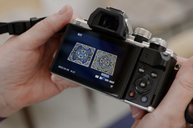 Digital camera being held up to show two embroideries on the screen